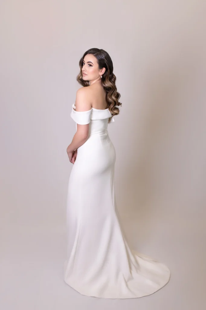 Back view of bride in an off-the-shoulder wedding dress with soft curls