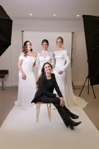 Group photo of three brides in different gowns posing with the hairstylist