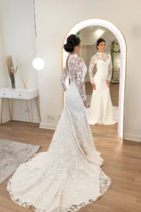 Bride admiring her reflection in a mirror while wearing a lace long-sleeve wedding dress