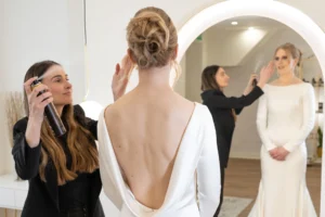 Bride with an elegant updo receives final styling touches for her open-back wedding gown