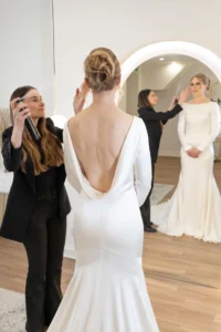 Bride with an elegant updo receives final styling touches for her open-back wedding gown