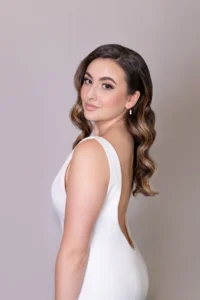 Bride in low-back gown with glamorous waves hairstyle, facing to the side