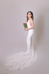 Bride in full-length low-back wedding gown holding tulip bouquet