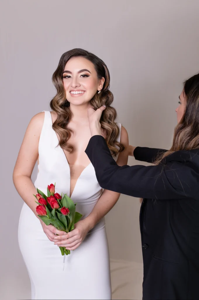 Bridal stylist adjusting the bride's soft curls during final photoshoot touches