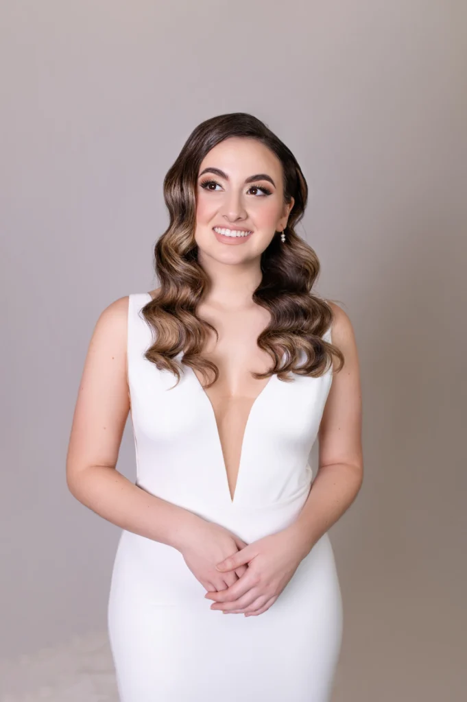 Bride in deep V-neck gown with soft waves hairstyle, looking to the side