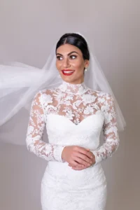 Bride in high-neck lace gown with vibrant red lipstick and flowing veil