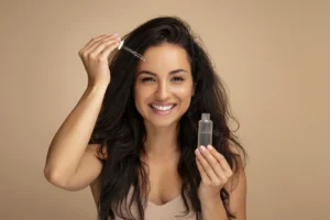 Smiling woman applying hair serum for healthy, shiny hair