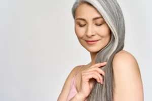 Mature woman with beautiful gray hair enjoying her hair care routine.