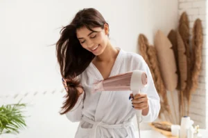 Woman drying her long, shiny hair with a modern hairdryer.