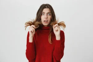 Worried woman showing split ends and damaged hair