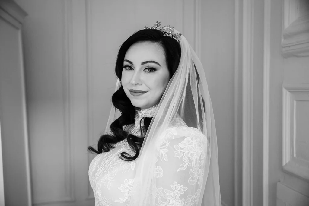 Elegant winter bride in a lace gown with soft curls and a delicate veil, ready for a winter wonderland wedding.