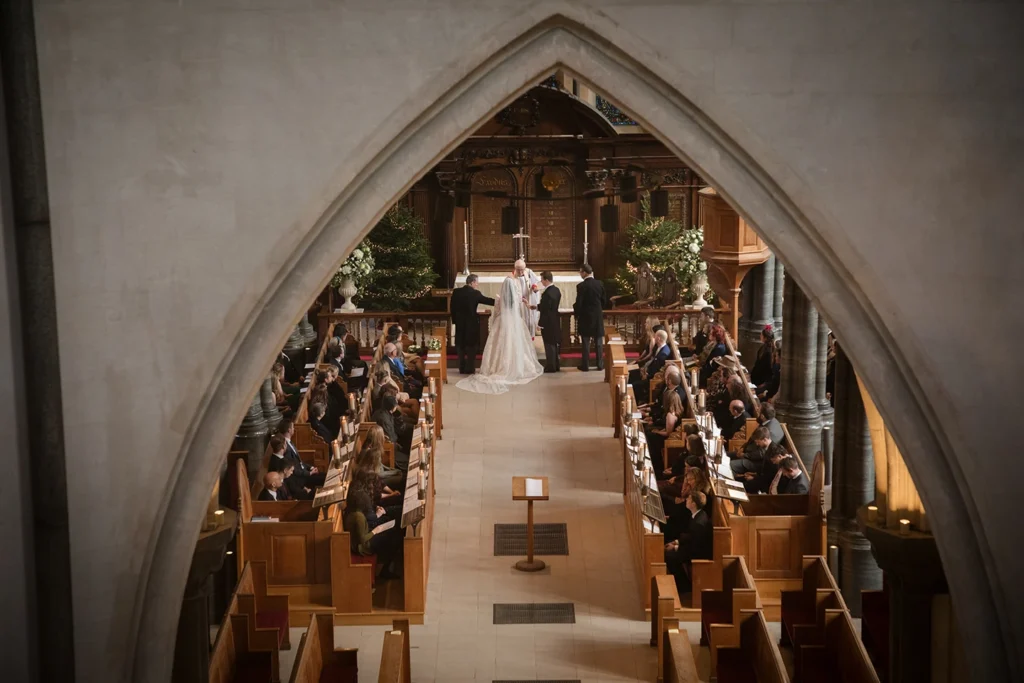 Winter wedding ceremony captured through a gothic arch at a historic church.