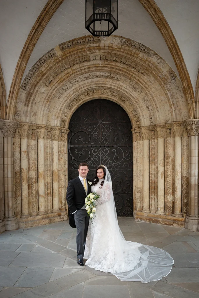 Newlywed couple standing in front of an intricately designed historic archway for their winter wedding.