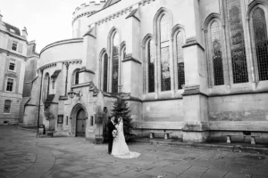 Bride and groom posing outside a grand historic venue, surrounded by winter charm.