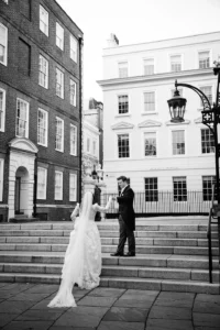 Bride and groom sharing a graceful moment on the steps of a historic building during their winter wedding.