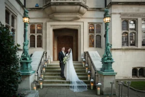 Bride and groom posing on candlelit steps outside a regal venue, highlighting the winter wonderland ambiance.