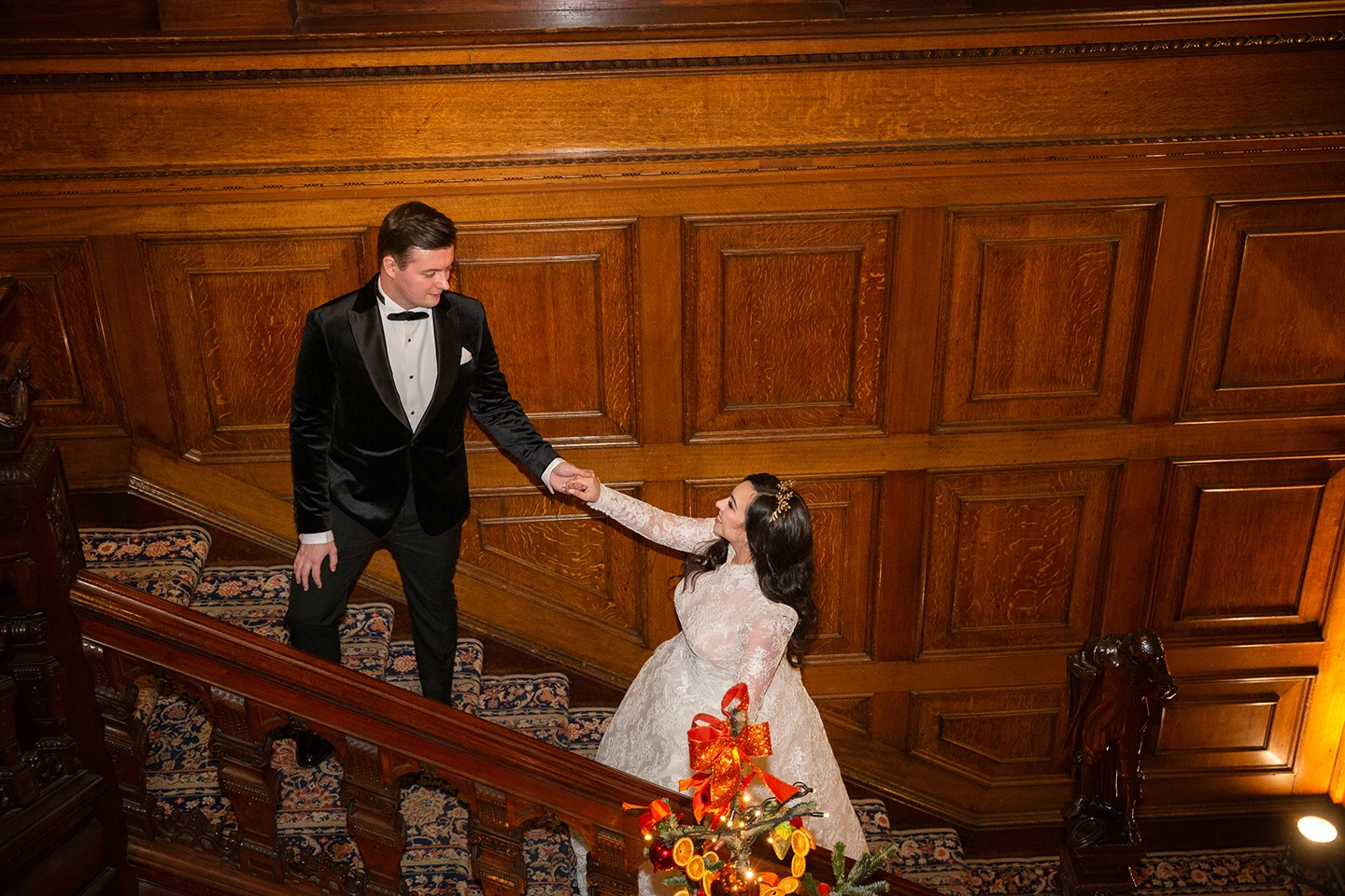 Bride and groom sharing a romantic moment on a grand staircase surrounded by winter-themed decor.