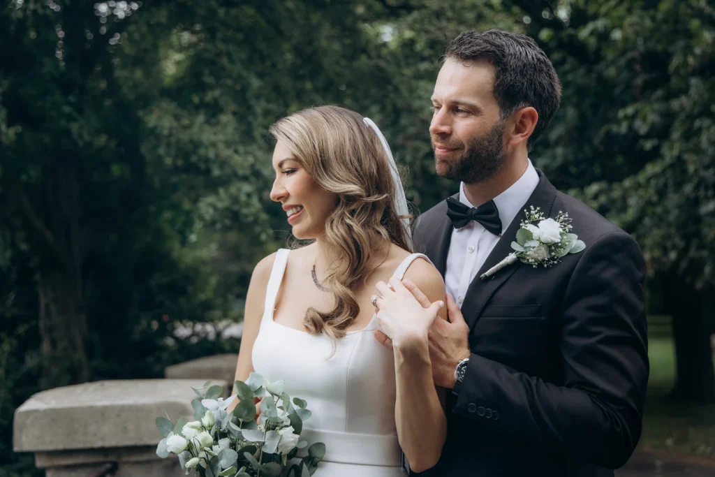 Romantic close-up of bride and groom holding hands against a tree near Fulham Library.