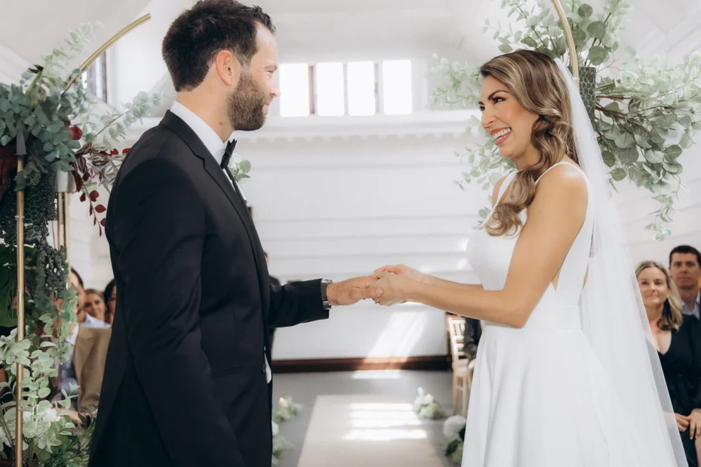 Bride smiling as the groom holds her hand during vows at Fulham Library