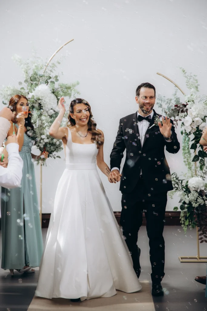 Bride and groom walking through bubbles at Fulham Library wedding celebration.