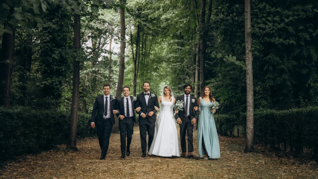 Wedding party walking through a tree-lined pathway