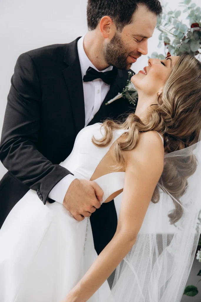 Groom leaning in for a romantic moment with the bride, showcasing her flowing veil.