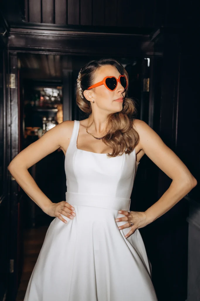 Bride wearing heart-shaped sunglasses, striking a playful pose at Fulham Library.