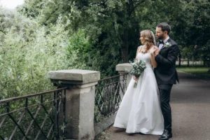 Bride and groom on a scenic bridge surrounded by greenery.