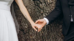 Close-up of bride and groom holding hands under a large tree during their Fulham Library wedding.