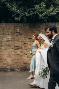 Bride walking with her bridesmaid and groomsman on a charming pathway