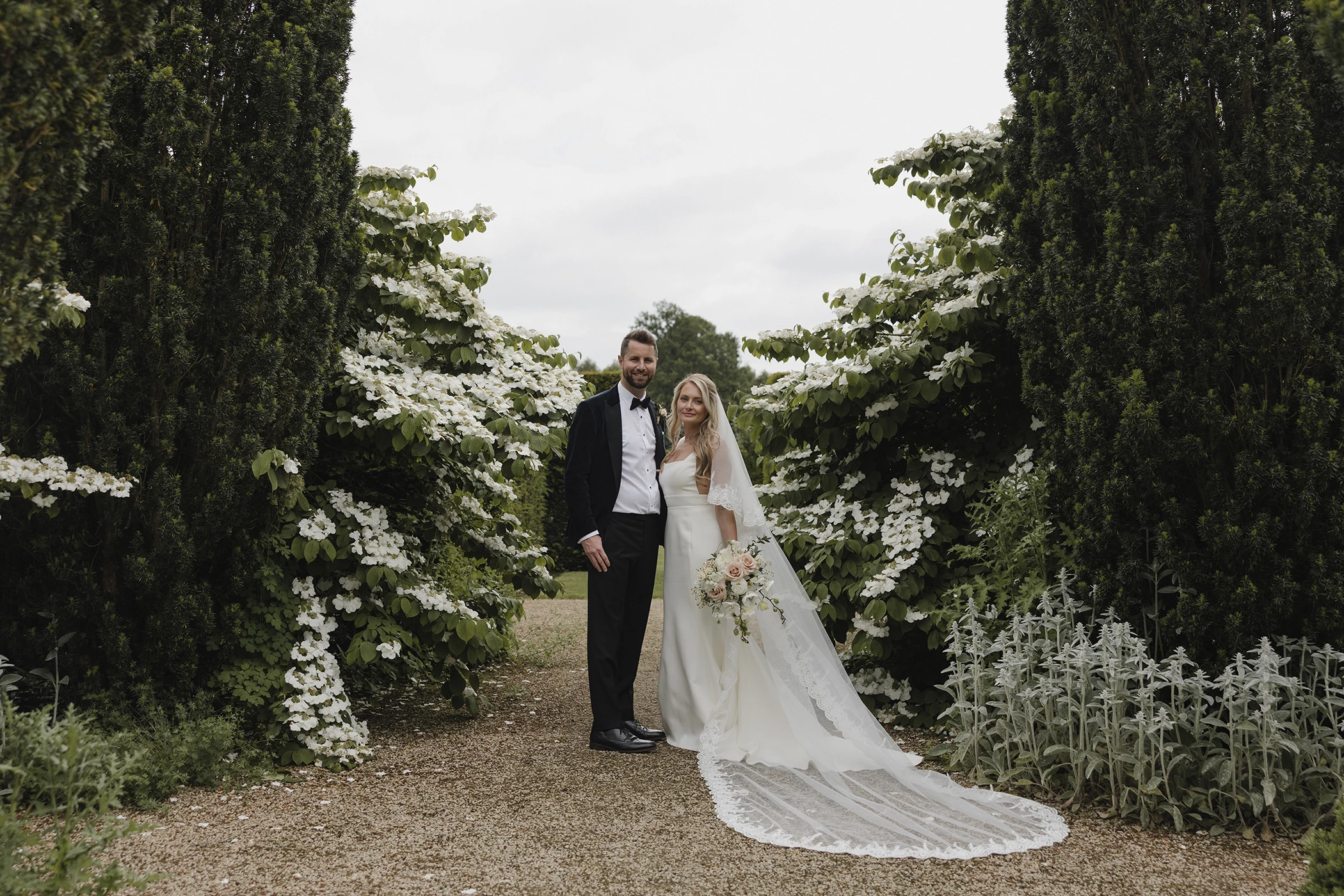 Bride and groom framed by floral archway at Loseley Park.