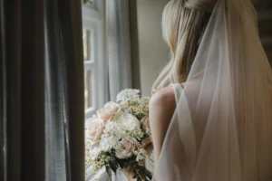 Bride holding bouquet and looking out the window at Loseley Park