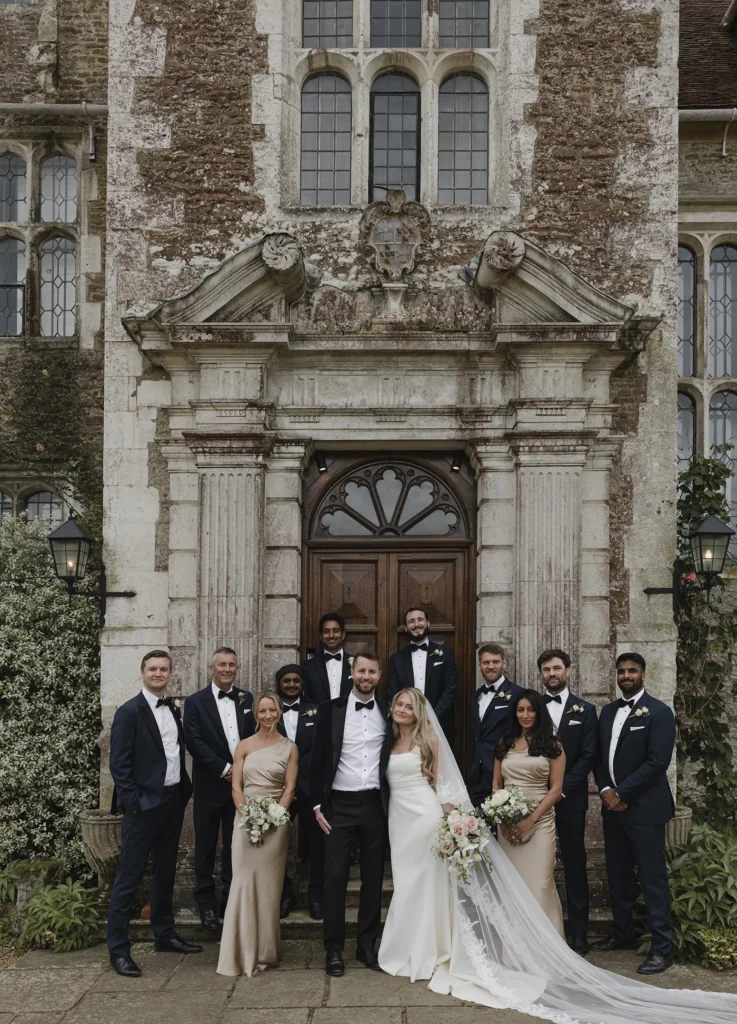 Bride and groom with wedding party in front of Loseley Park manor