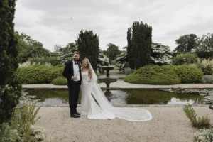 Bride and groom posing by the fountain in Loseley Park gardens