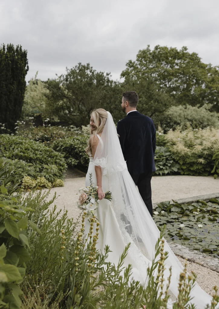 Bride and groom walking in the serene gardens of Loseley Park.