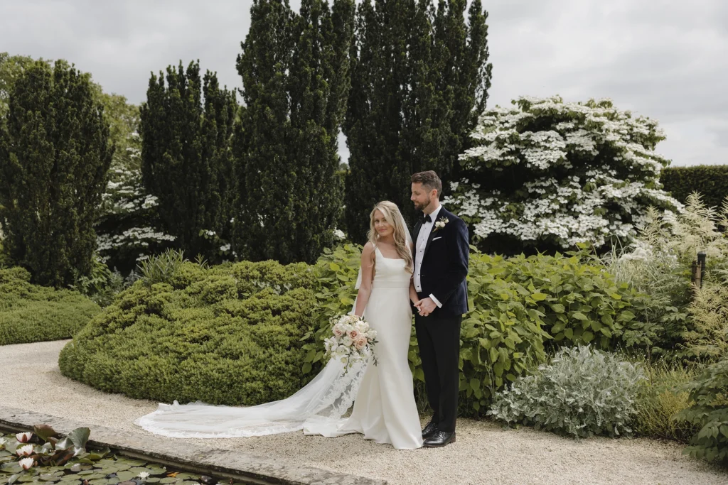 Bride and groom posing among lush greenery at Loseley Park.