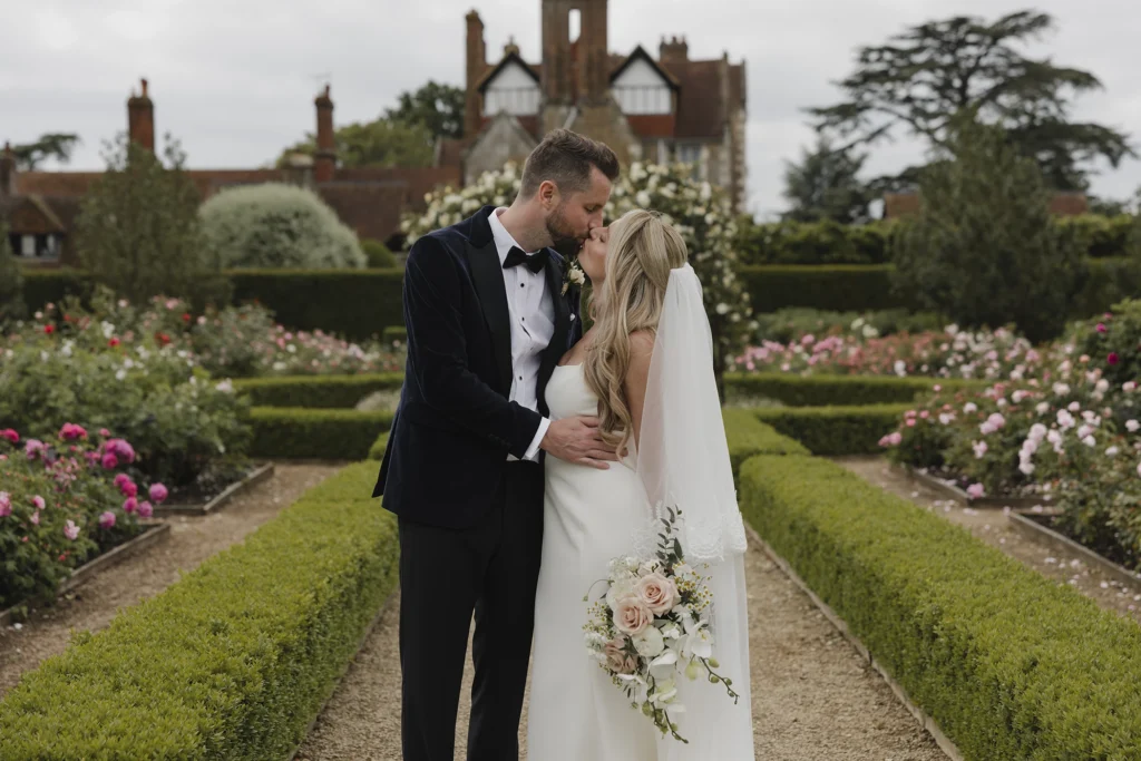 Bride and groom sharing a kiss in the Loseley Park gardens.