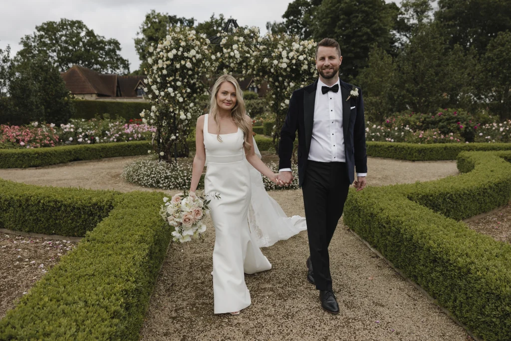 Bride and groom holding hands while walking through the Loseley Park grounds.