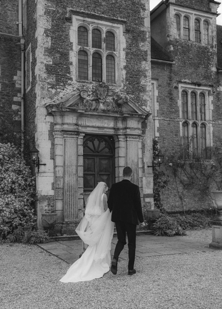 Bride and groom walking towards the historic Loseley Park manor.