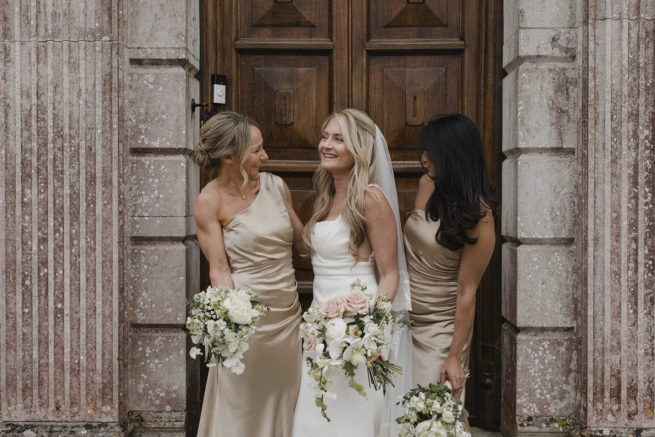 Bride laughing with bridesmaids in gold dresses at Loseley Park