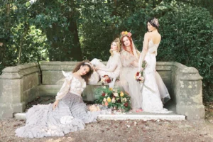 Four brides posing gracefully on a garden bench surrounded by floral decorations at Nutfield Priory.