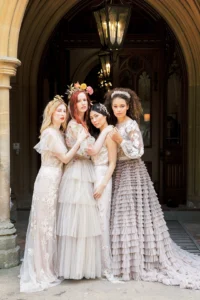 Brides in intricate gowns standing together under the elegant entrance of Nutfield Priory.