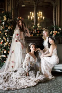 Four brides in luxurious gowns with intricate floral details, posing in an elegant interior setting at Nutfield Priory.