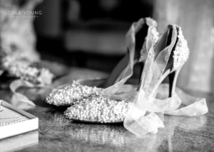 Close-up of embellished bridal heels with pearls and lace during a Pelham House wedding photoshoot.