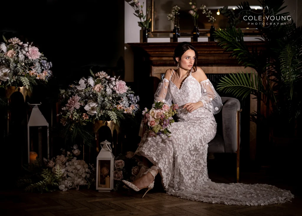 Bride seated with lush floral arrangements during Pelham House wedding photoshoot.