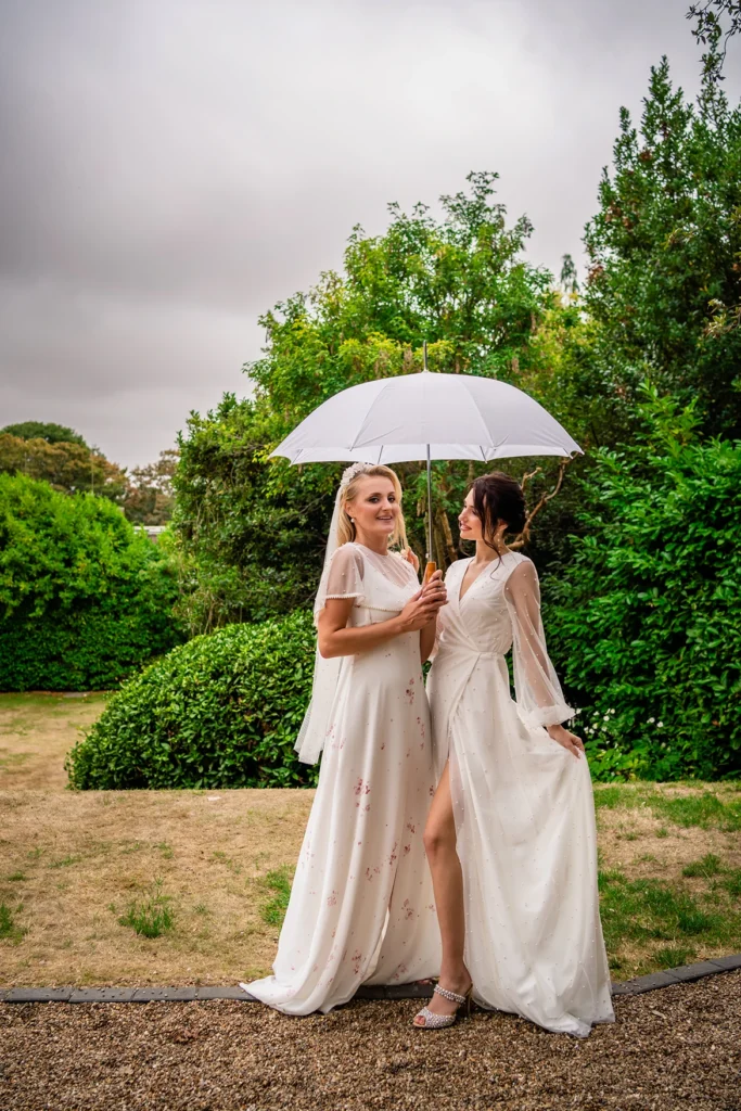 Two brides posing with a white umbrella during the Pelham House bridal photoshoot.