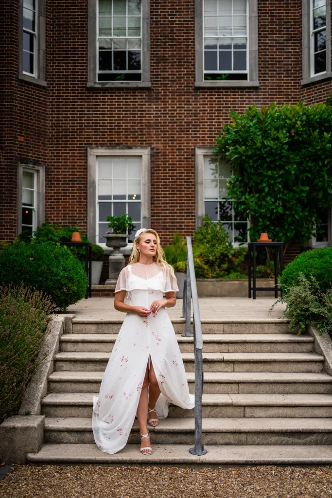 A bride gracefully walking down the steps of Pelham House during the photoshoot.