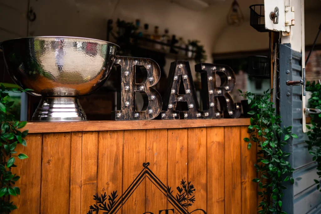 Close-up of a rustic bar at Pelham House with decorative lights and greenery.