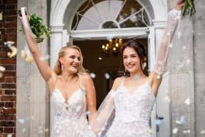 Joyful brides celebrating with confetti at Pelham House entrance