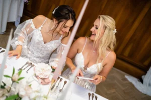 Brides sharing a laugh at the reception table during Pelham House shoot